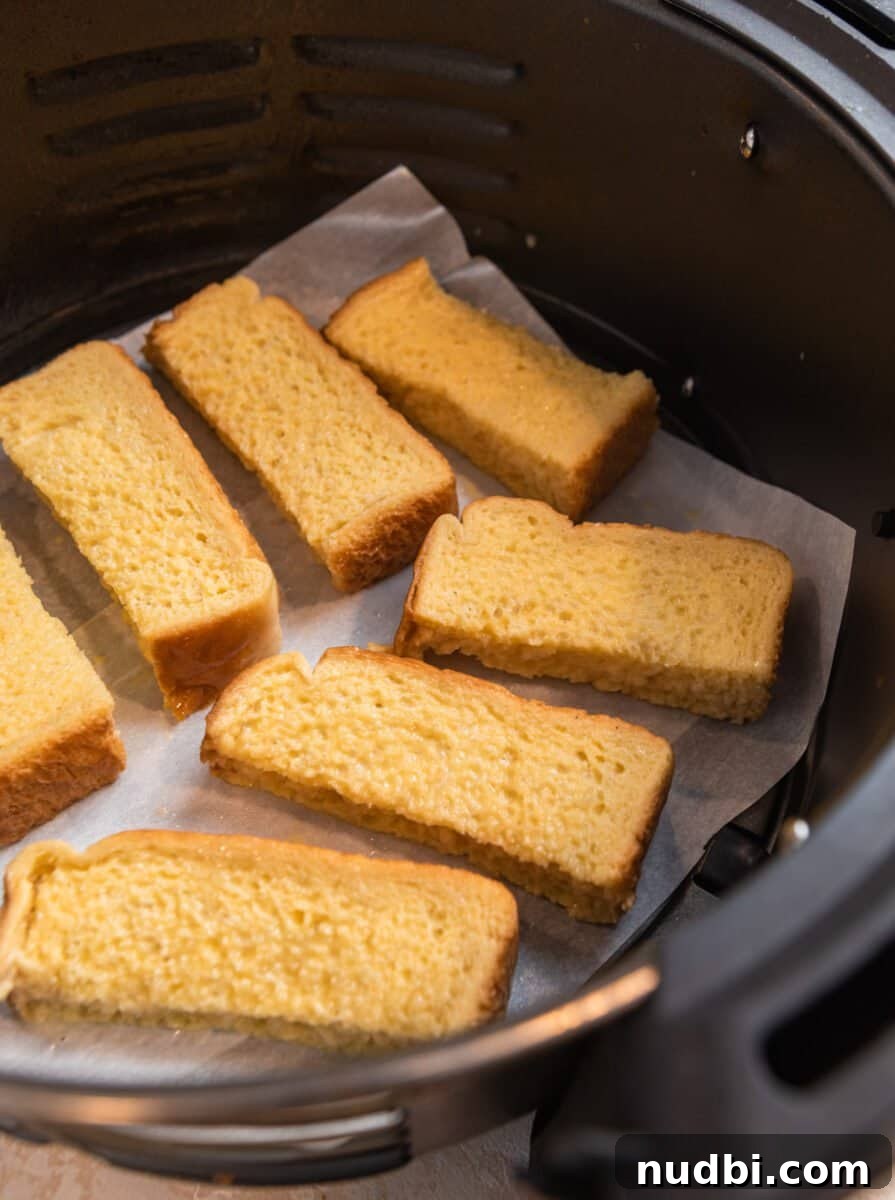 Crispy Air Fryer French Toast Sticks Recipe 6 French toast sticks lined in air fryer basket before being cooked.