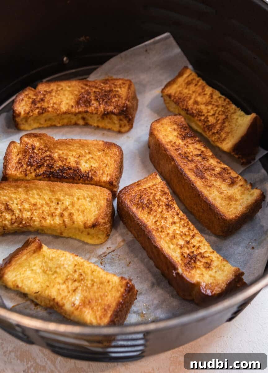 Crispy Air Fryer French Toast Sticks Recipe 7 French toast sticks lined in air fryer basket after being cooked.