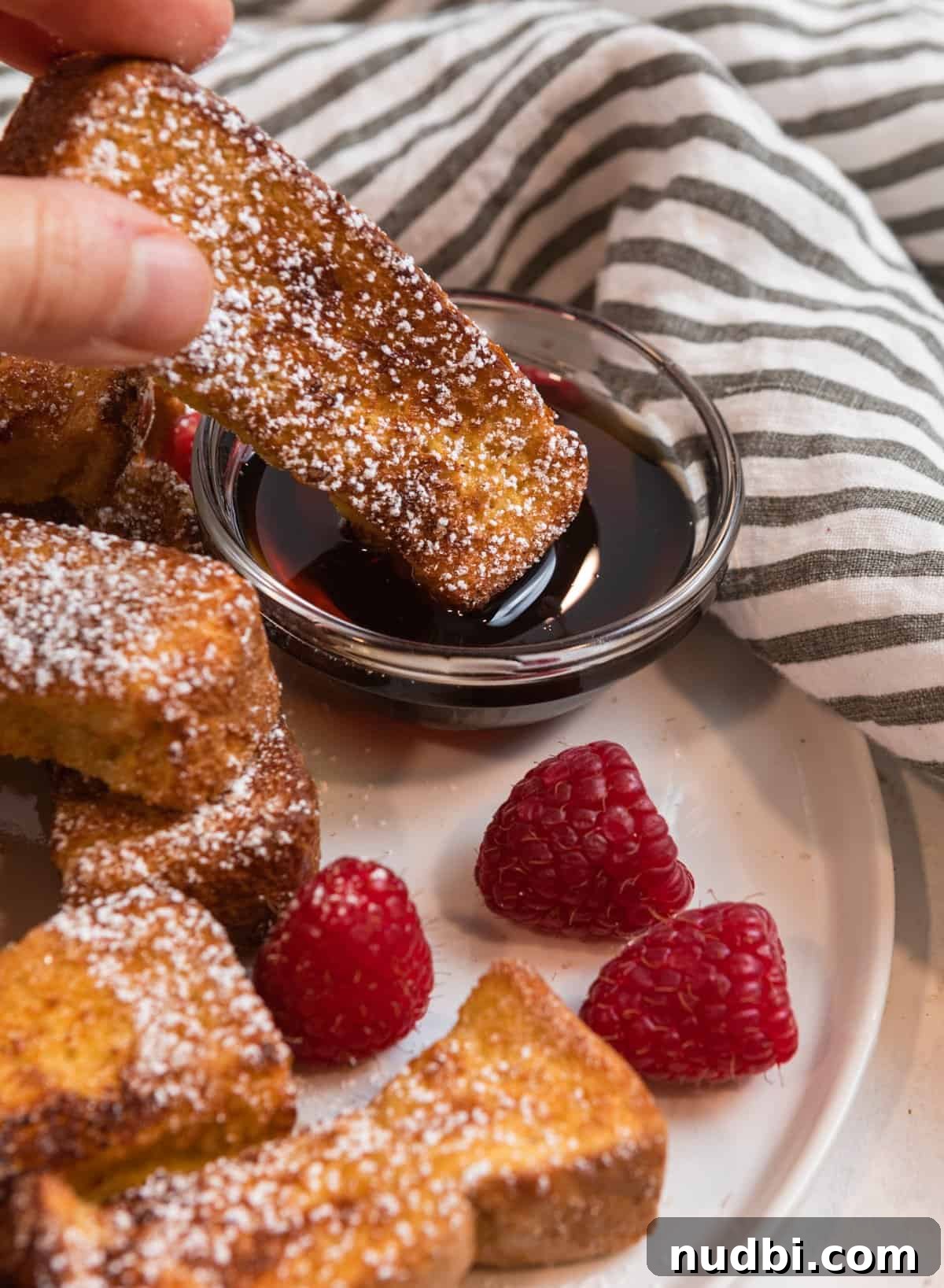 Crispy Air Fryer French Toast Sticks Recipe 9 French toast stick being dunked into dish with maple syrup.