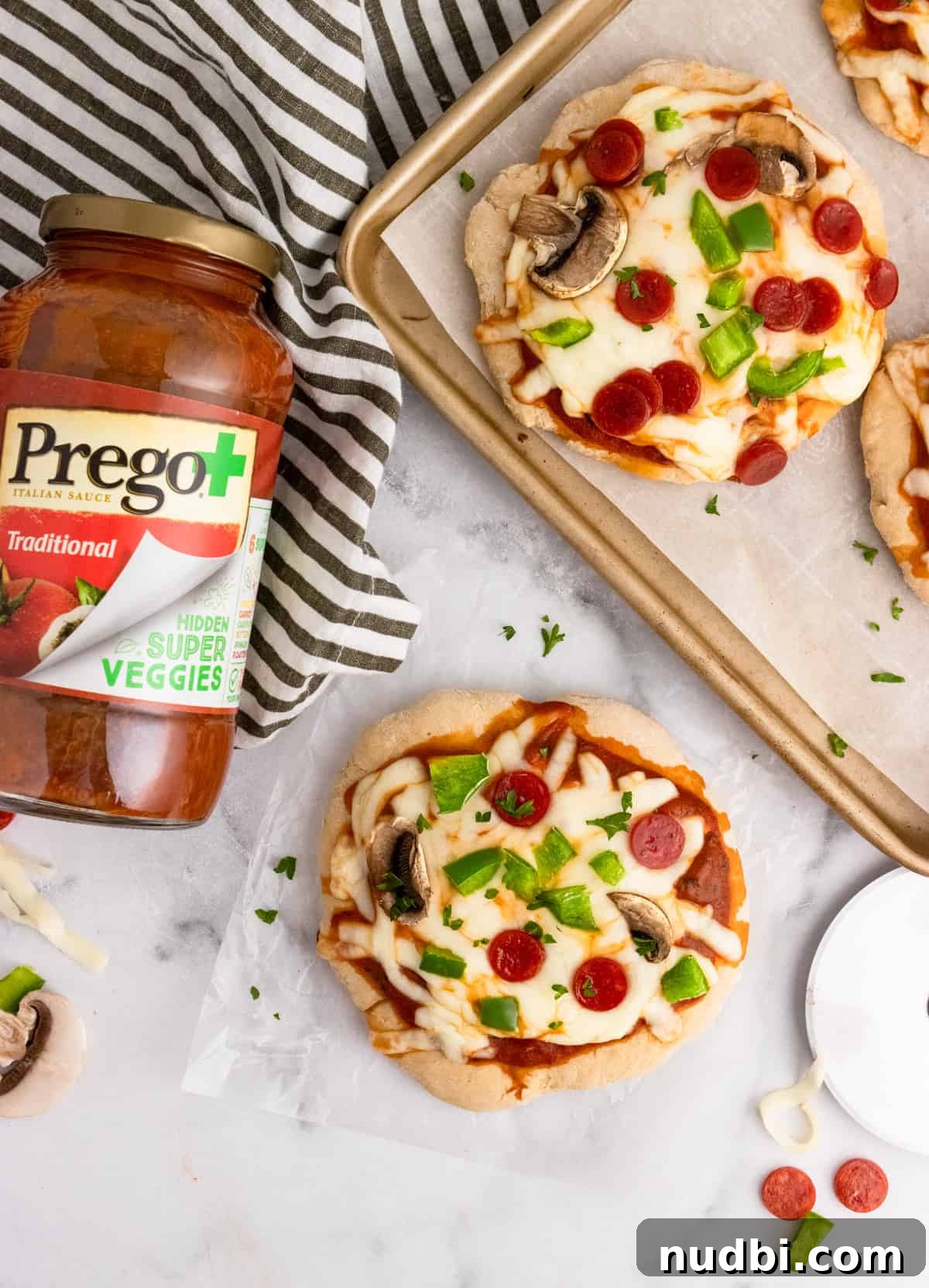 Whole Wheat Mini Veggie-Packed Pizzas for Kids 2 Overhead shot of pizzas on pan with tomato sauce jar.
