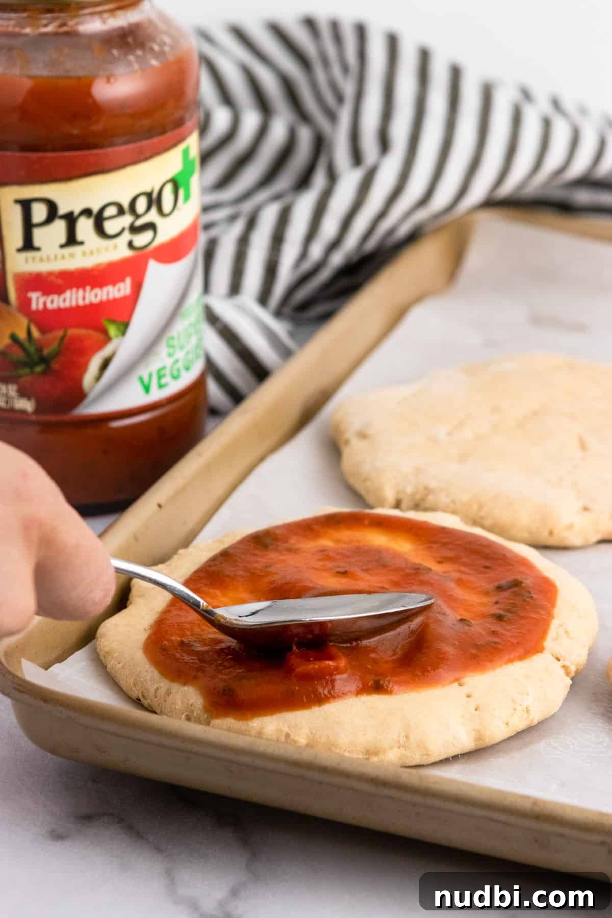Whole Wheat Mini Veggie-Packed Pizzas for Kids 8 Sauce spread onto pizza dough.