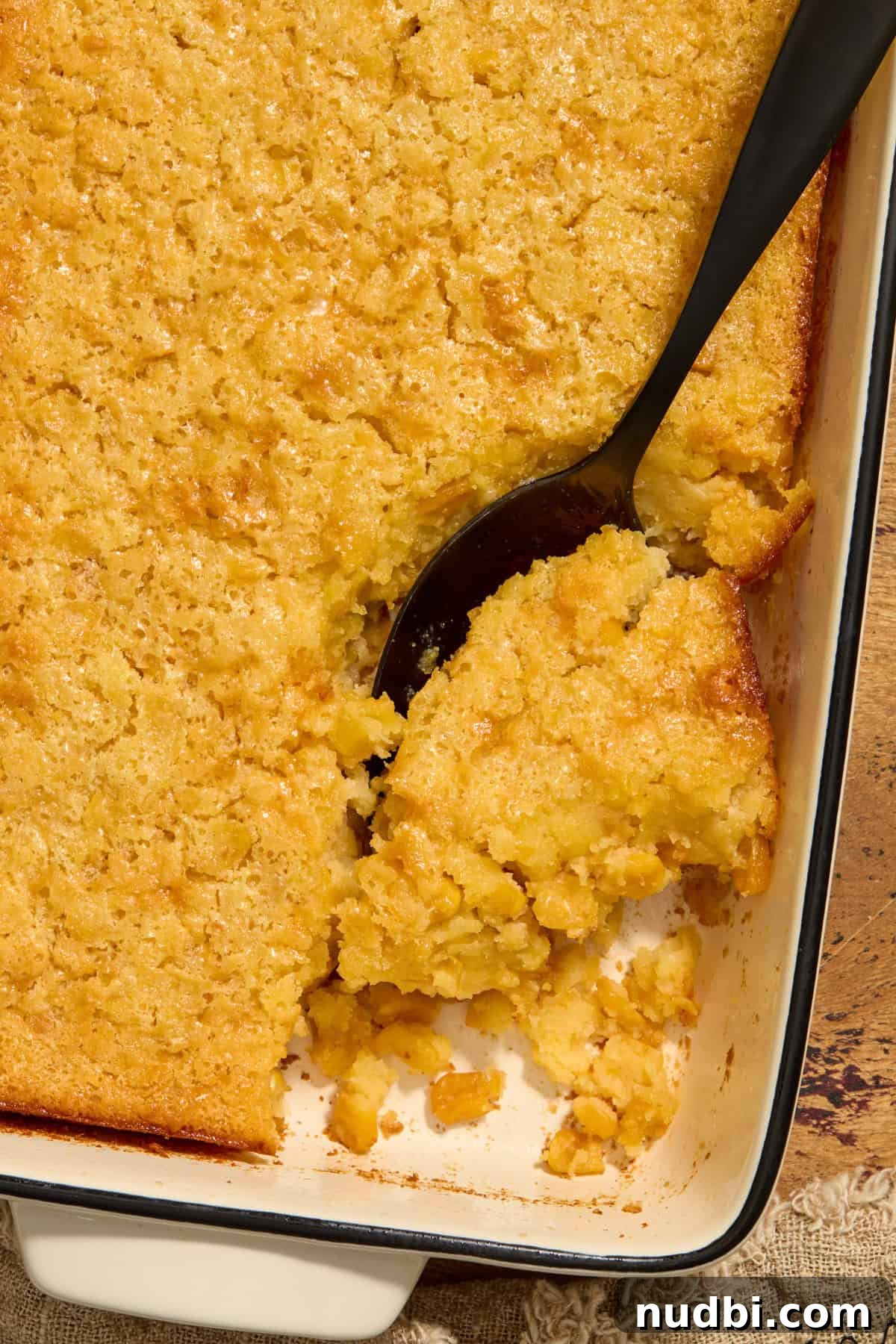 Sweet Honey Cornbread Casserole Recipe for Comforting Family Meals 11 Cornbread casserole in dish with serving spoon scooping in.
