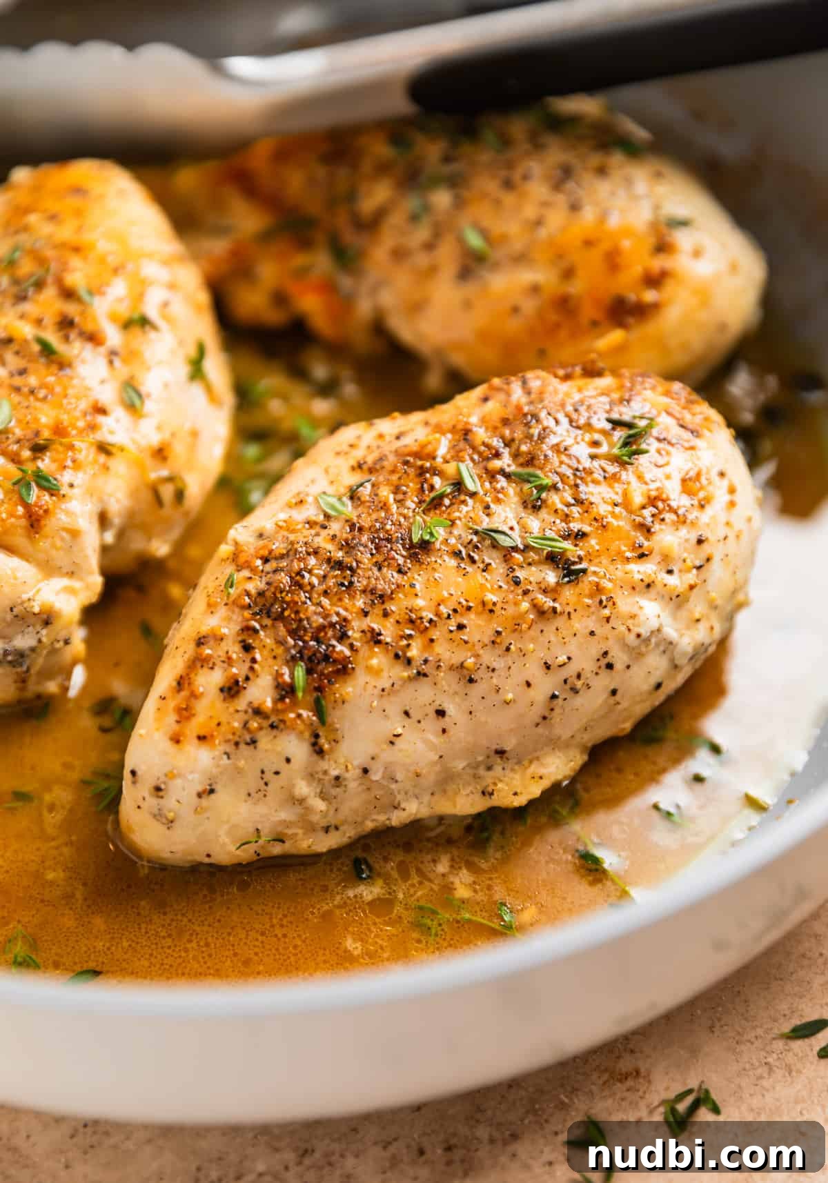 Simple White Wine Chicken Recipe for Weeknight Dinners 2 White wine chicken breasts in skillet topped with pepper and fresh thyme.