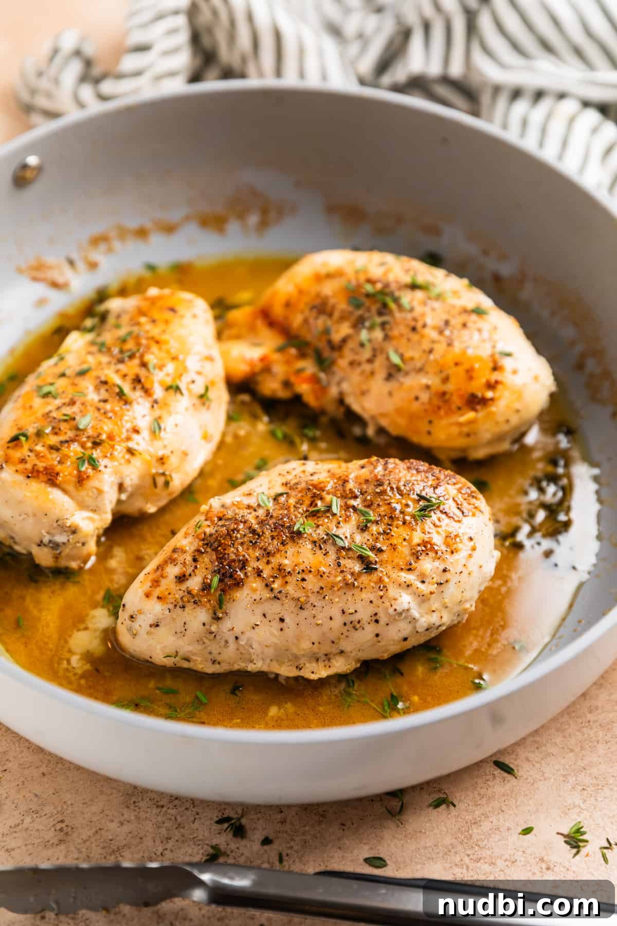 Simple White Wine Chicken Recipe for Weeknight Dinners 6 Cooked chicken breasts in skillet with white wine sauce with thyme sprigs.