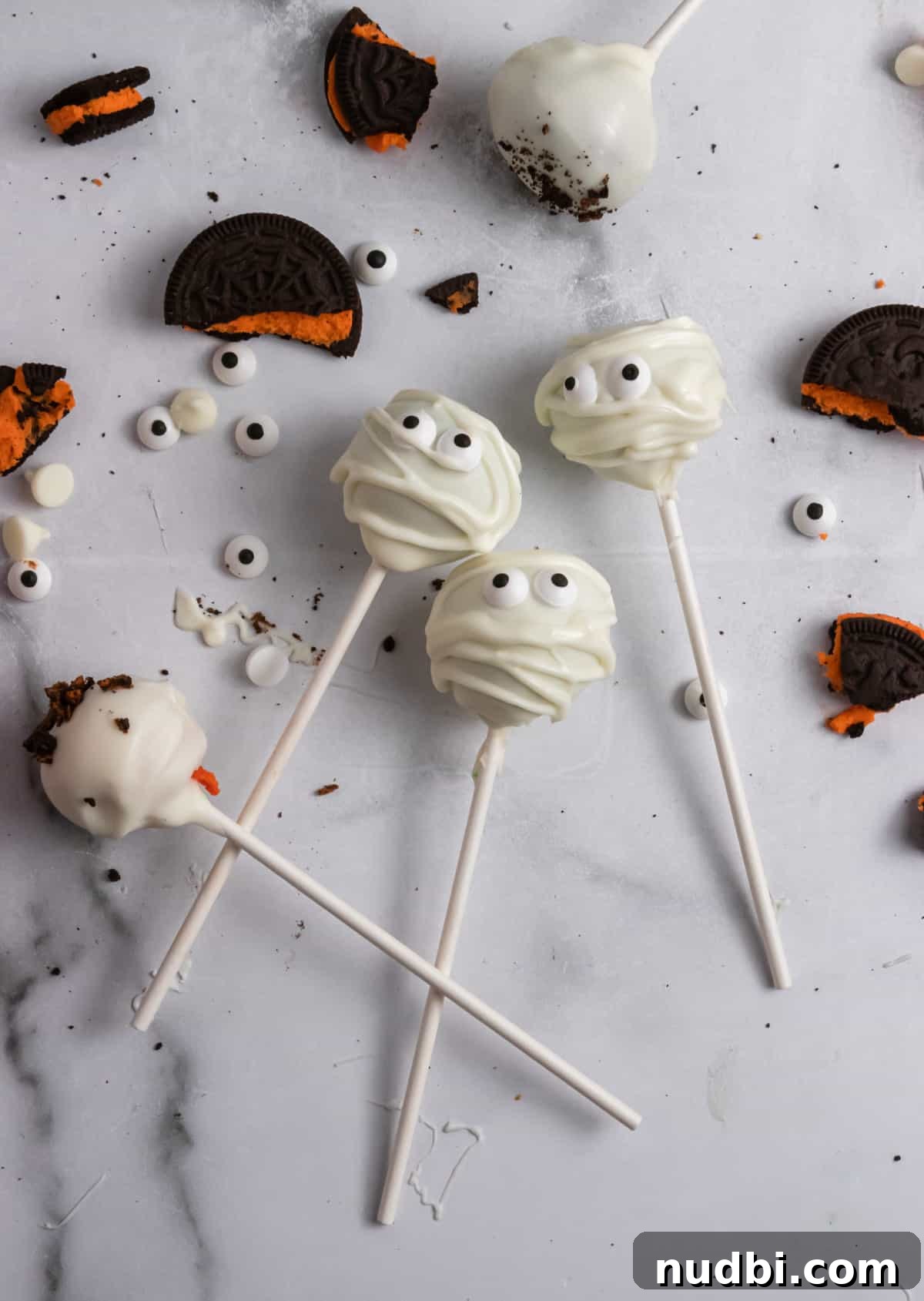 Spooky Halloween Cake Pop Ideas for Parties and Treats 3 Oreos and cake pops on counter with white chocolate chips and eyeballs.