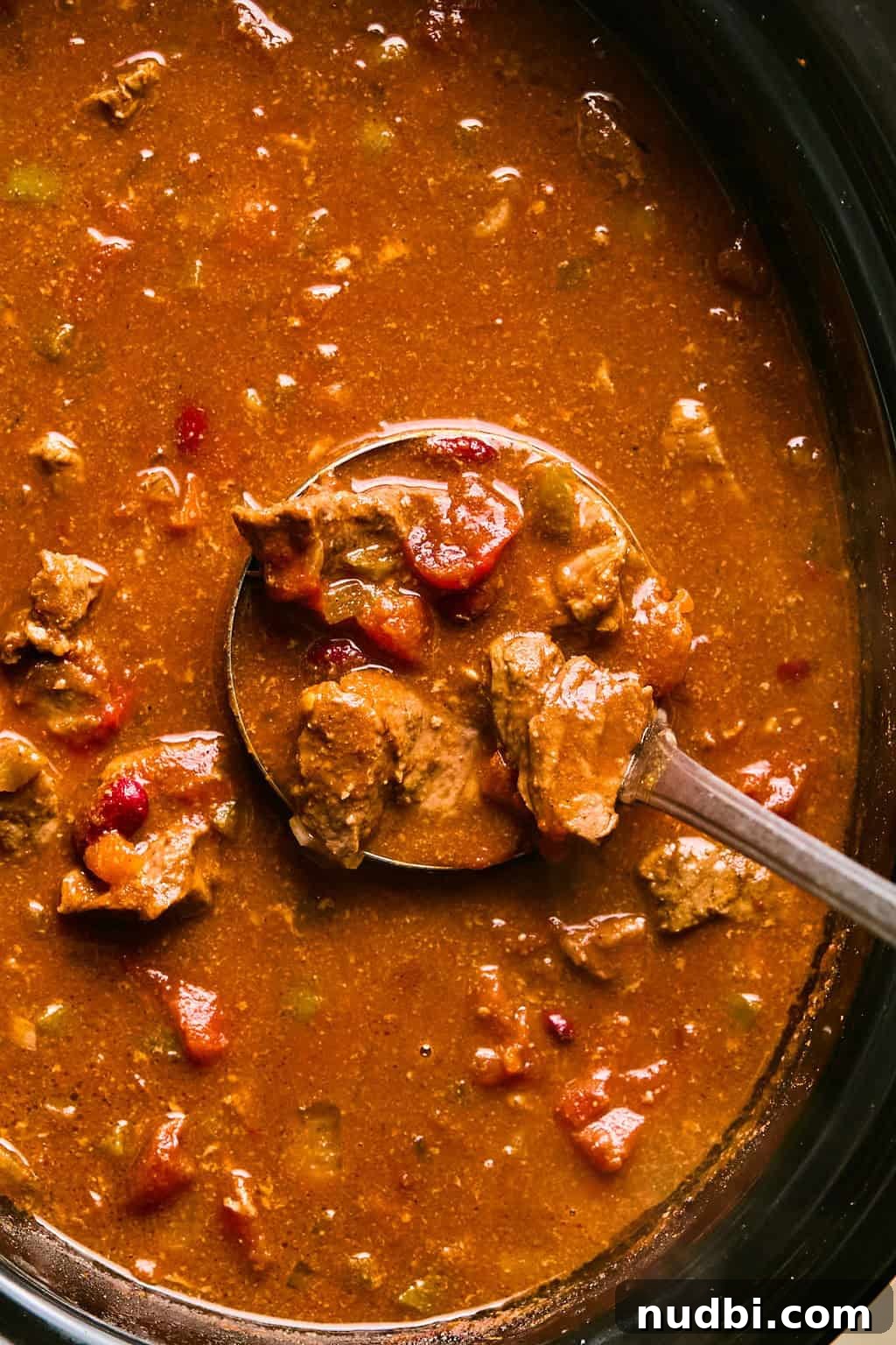 Slow Cooker Beef Brisket Chili Recipe for Tender, Smoky Flavor 11 Ladleful of brisket chili being pulled out of crockpot.