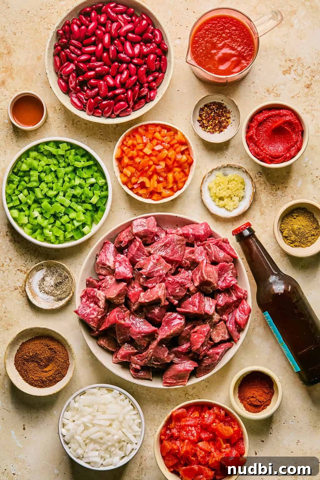 Slow Cooker Beef Brisket Chili Recipe for Tender, Smoky Flavor 3 Cubed beef brisket, beans, tomatoes, peppers, beer bottle and other ingredients needed to make recipe.