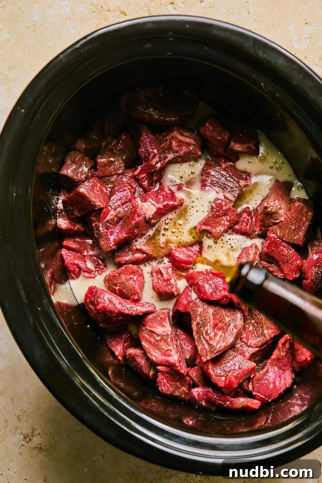 Slow Cooker Beef Brisket Chili Recipe for Tender, Smoky Flavor 5 Beer being poured into slow cooker over beef and seasoning.