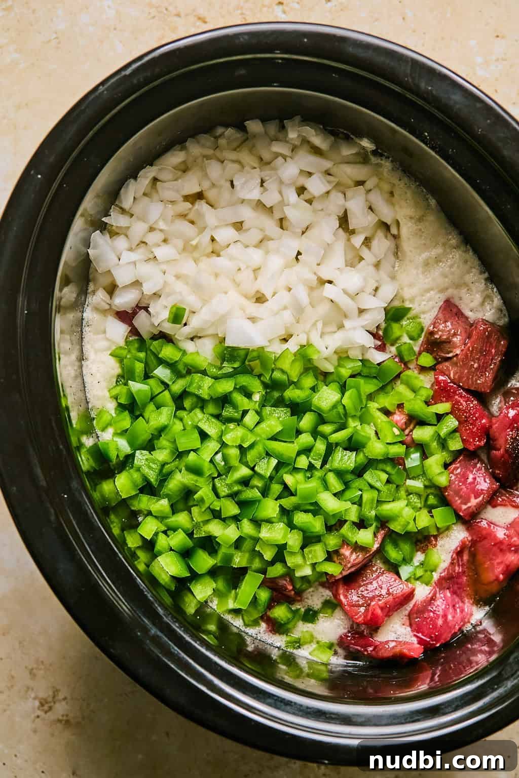 Slow Cooker Beef Brisket Chili Recipe for Tender, Smoky Flavor 6 Green peppers and onion over top meat in slow cooker.