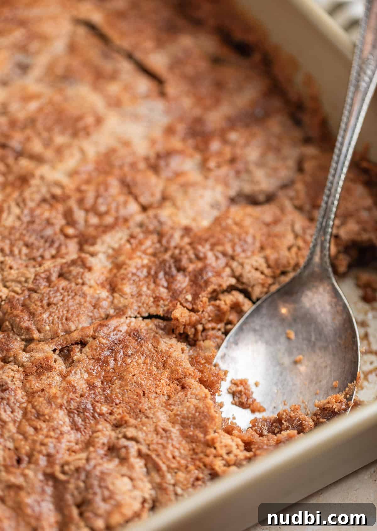 Classic Apple Dump Cake Recipe: Quick Homemade Comfort Dessert 7 Serving spoon scooping into pan with apple dump cake.