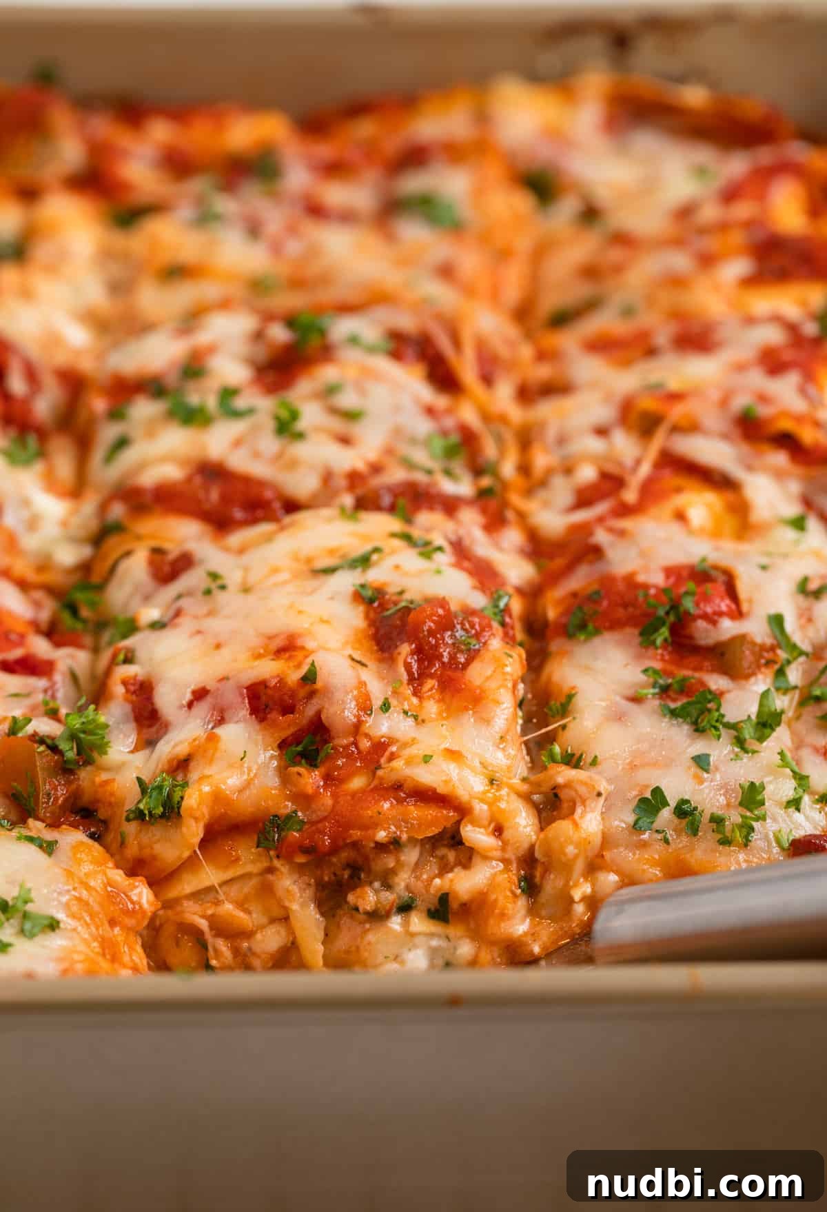 No-Boil Lasagna Recipe: Quick, Cheesy Oven-Baked Lasagna 9 Sliced lasagna made with meatballs with spatula placed in pan.