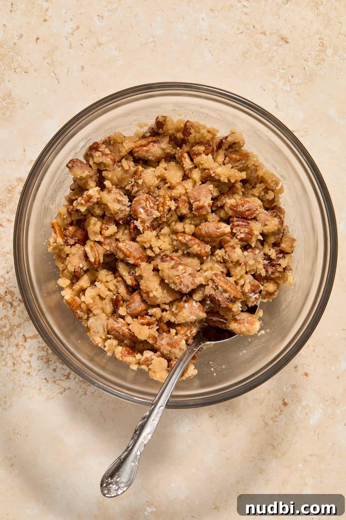 Creamy Butternut Squash Casserole with Sage and Parmesan 6 Pecan crumble mixture in mixing bowl with spoon.