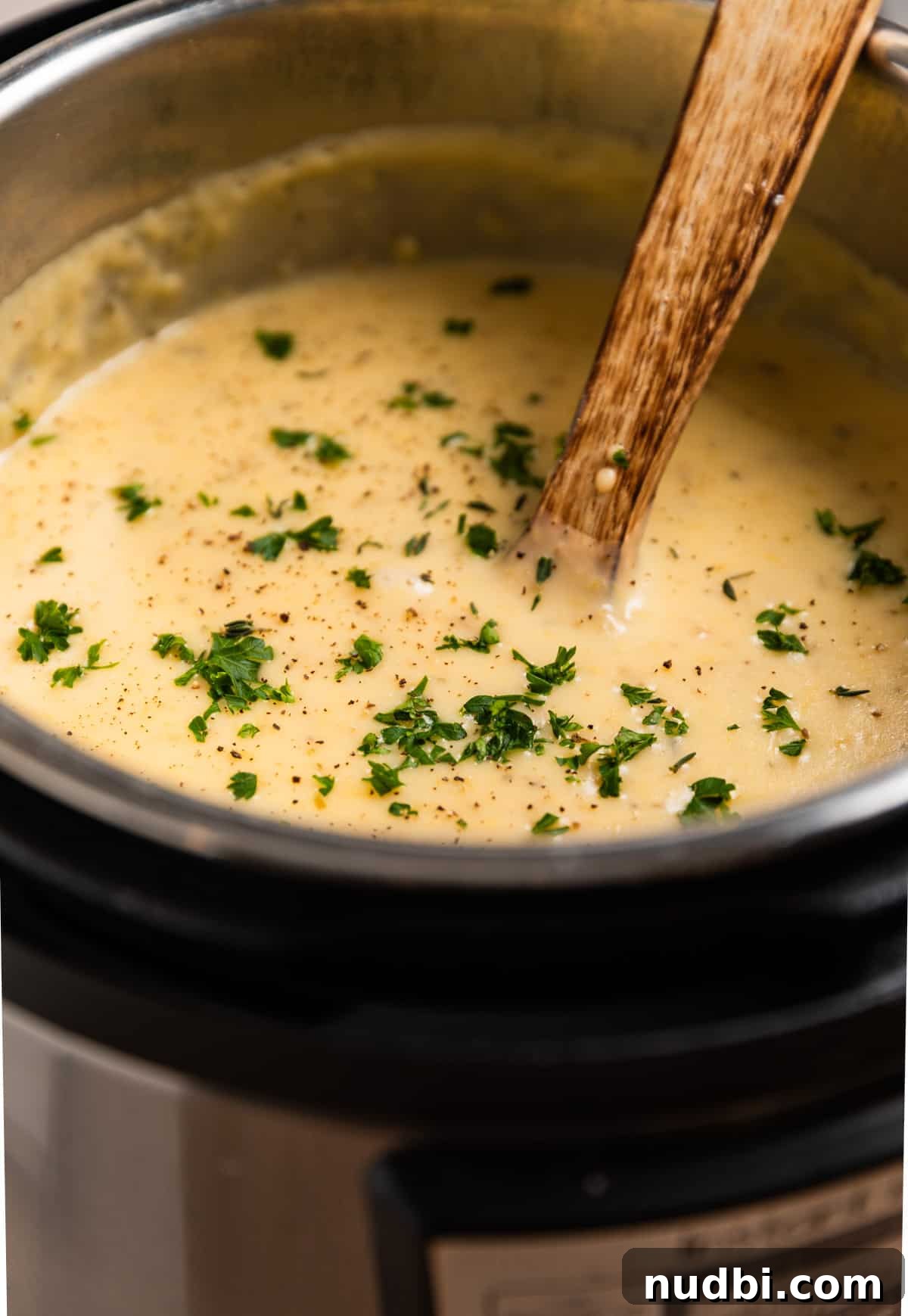 Creamy Instant Pot Potato and Leek Soup Recipe 7 Instant pot with soup topped with chopped parsley and wooden spoon inserted.
