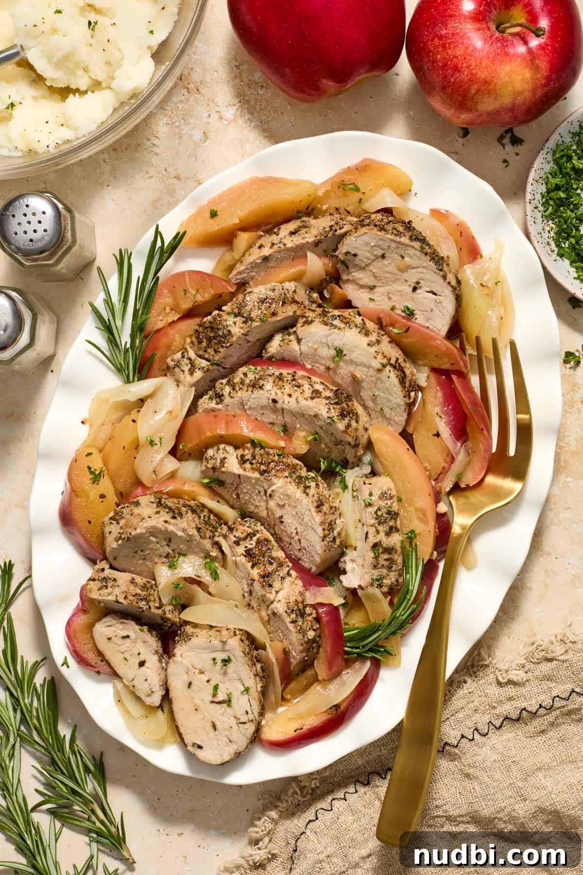 Juicy Instant Pot Pork Tenderloin Recipe for Quick Dinners 12 Serving platter with pork tenderloin slices, apples and rosemary.
