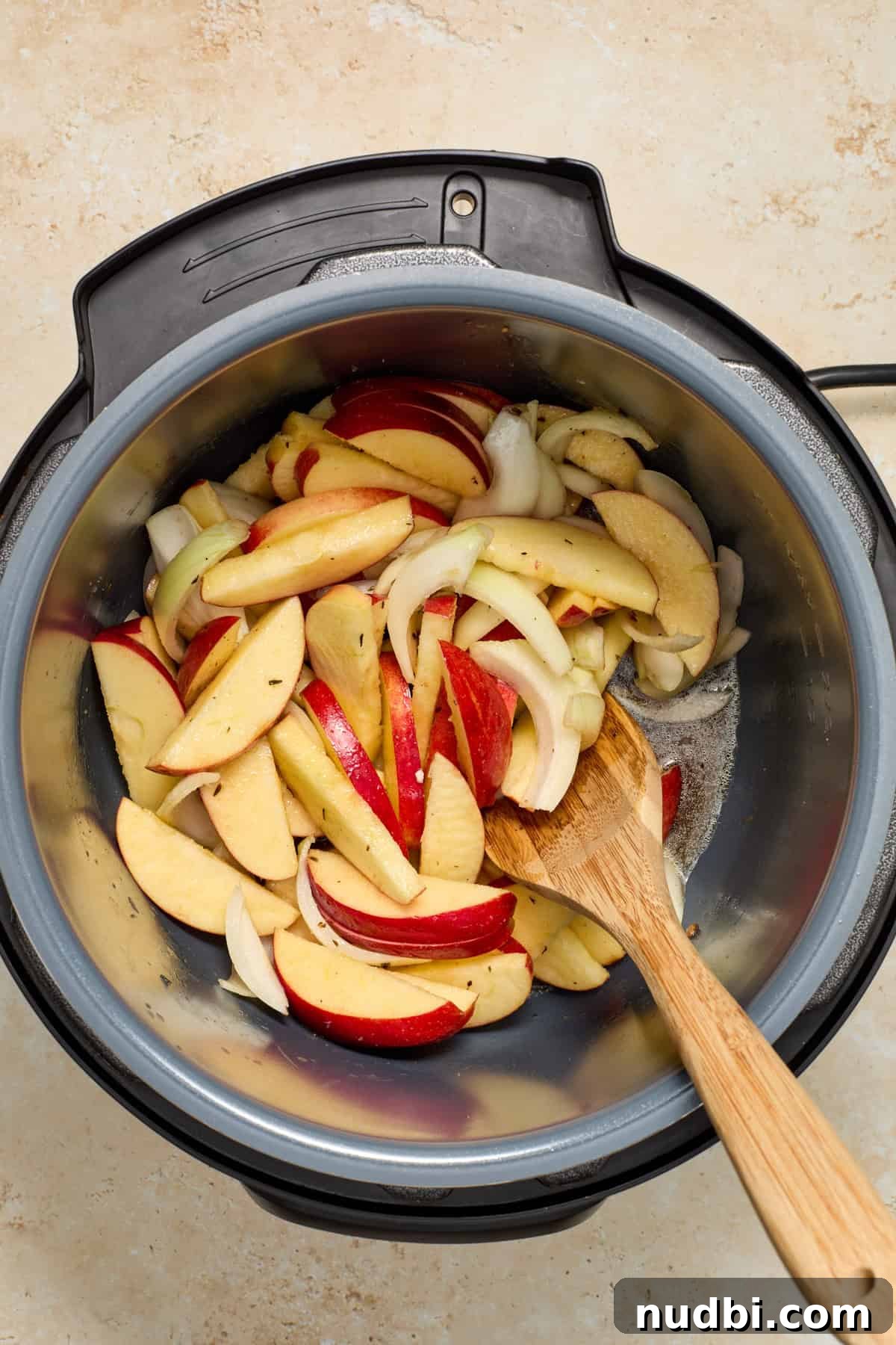 Juicy Instant Pot Pork Tenderloin Recipe for Quick Dinners 9 Apples, onion, butter and brown sugar added to pot with wooden spoon.