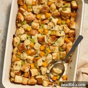Savory Butternut Squash Stuffing Recipe for Holiday Dinners 12 Butternut squash stuffing in pan with serving spoon scooping into the dish.