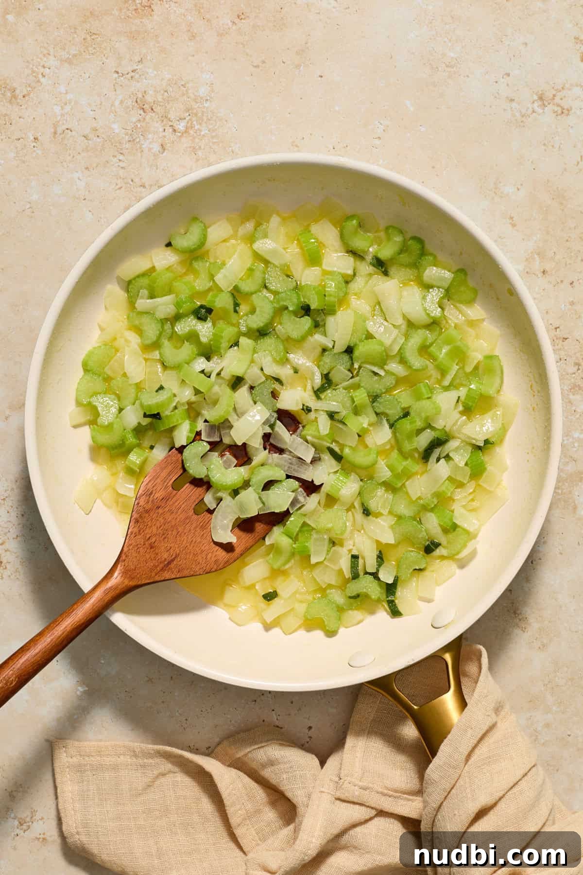 Savory Butternut Squash Stuffing Recipe for Holiday Dinners 4 Sautéed onion and celery in butter with herbs and wooden spatula.