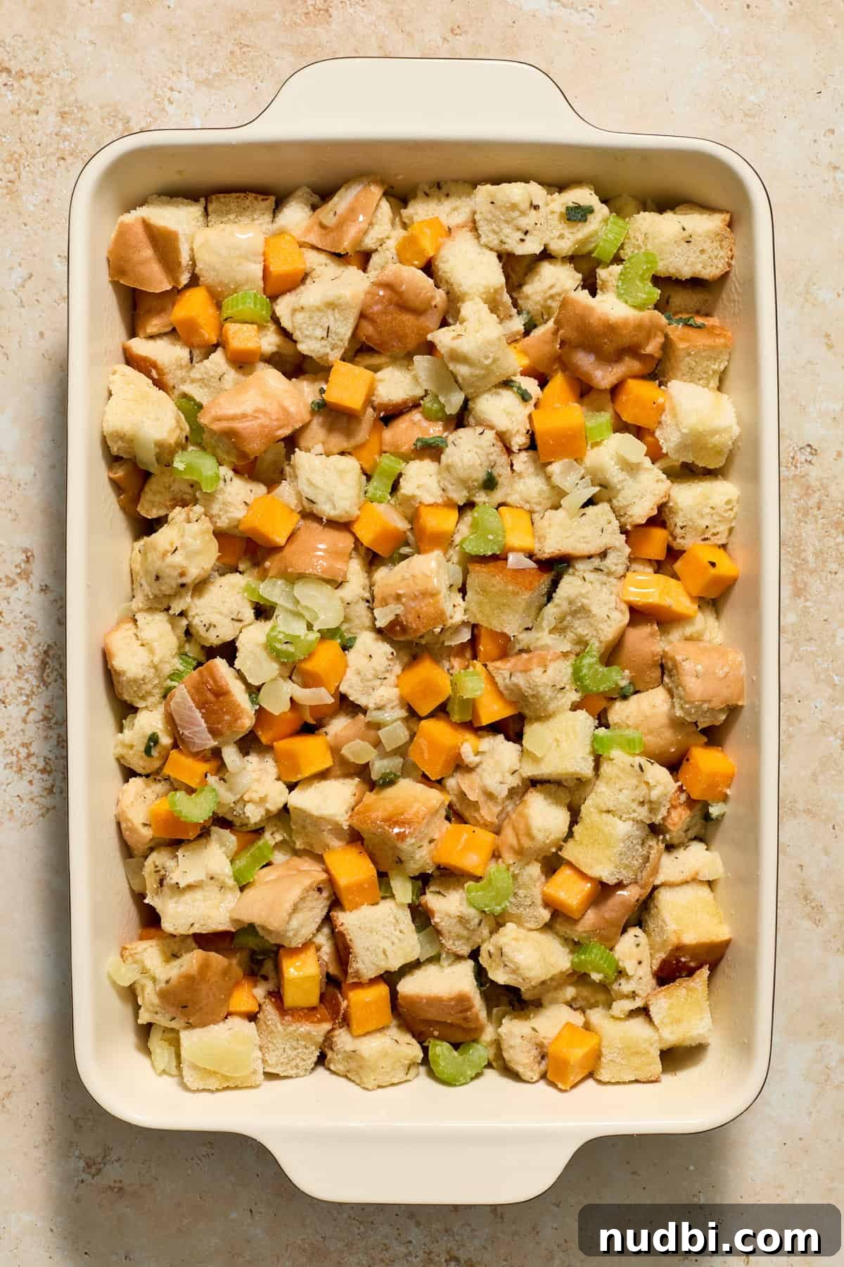 Savory Butternut Squash Stuffing Recipe for Holiday Dinners 8 Baking pan with stuffing ingredients before baking with melted butter drizzled over top.