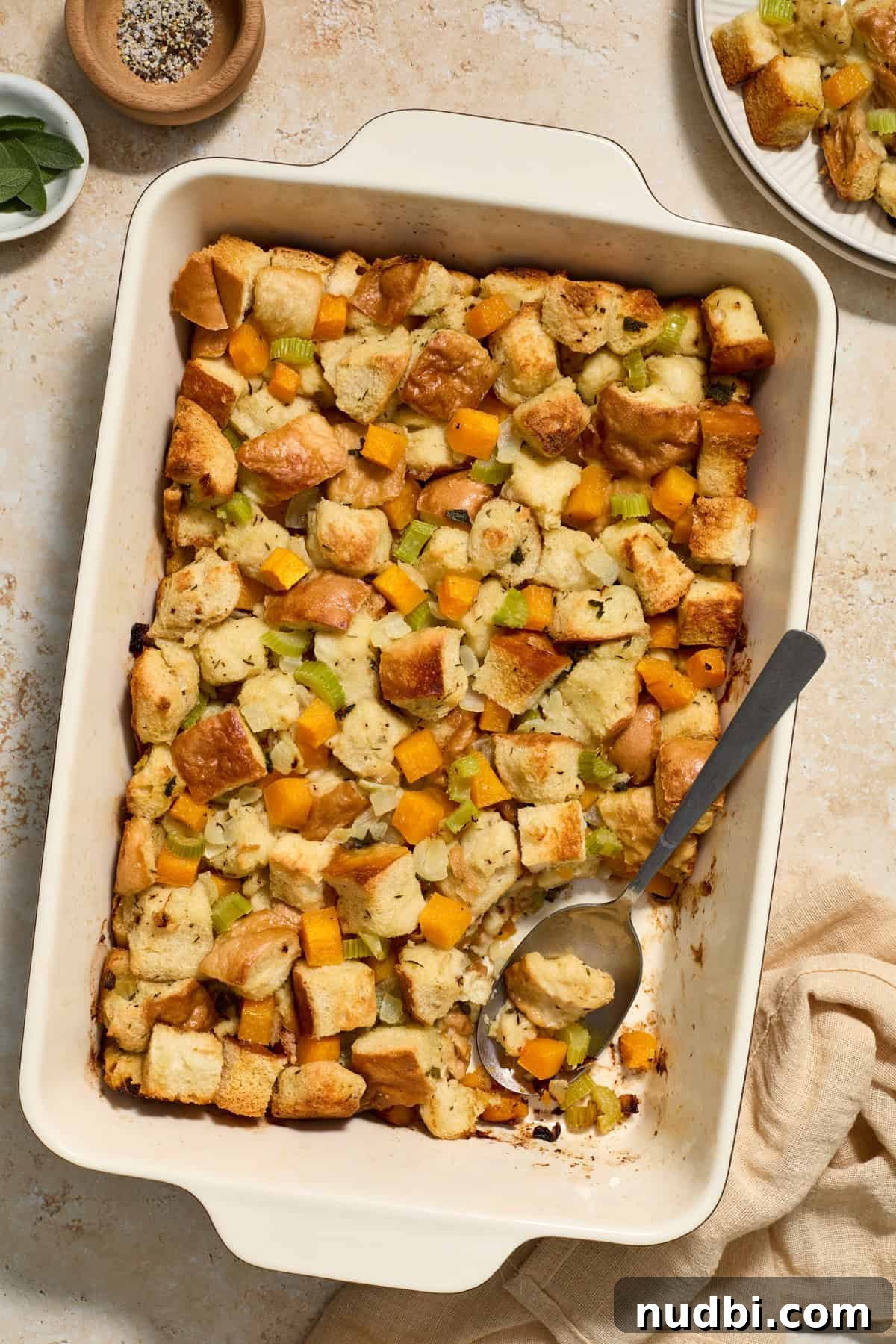 Savory Butternut Squash Stuffing Recipe for Holiday Dinners 10 Baking pan with baked butternut squash stuffing with spoon scooping into the dish.