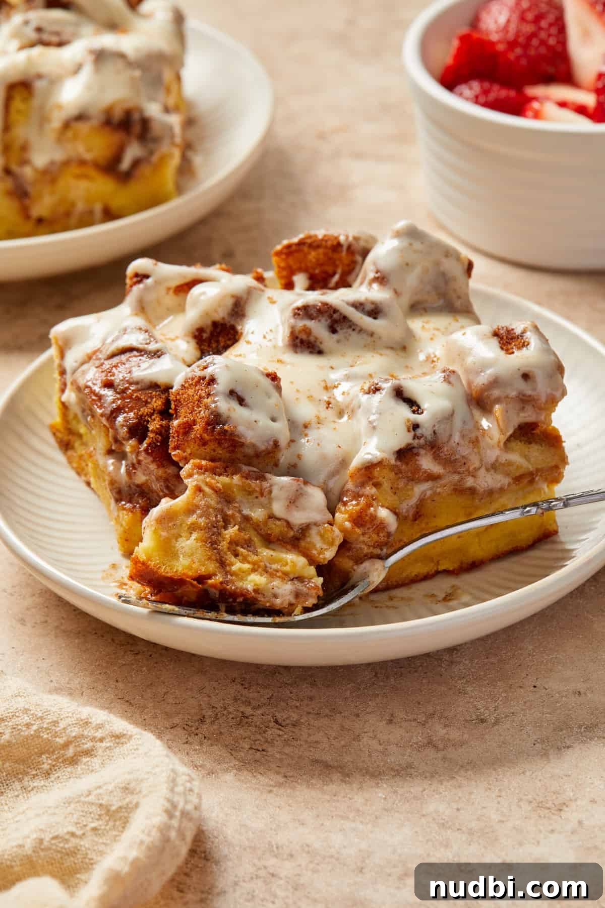 Cinnamon Roll Baked French Toast Recipe for Brunch 2 Cinnamon French toast casserole made with Brioche bread sliced on plate with forkful.