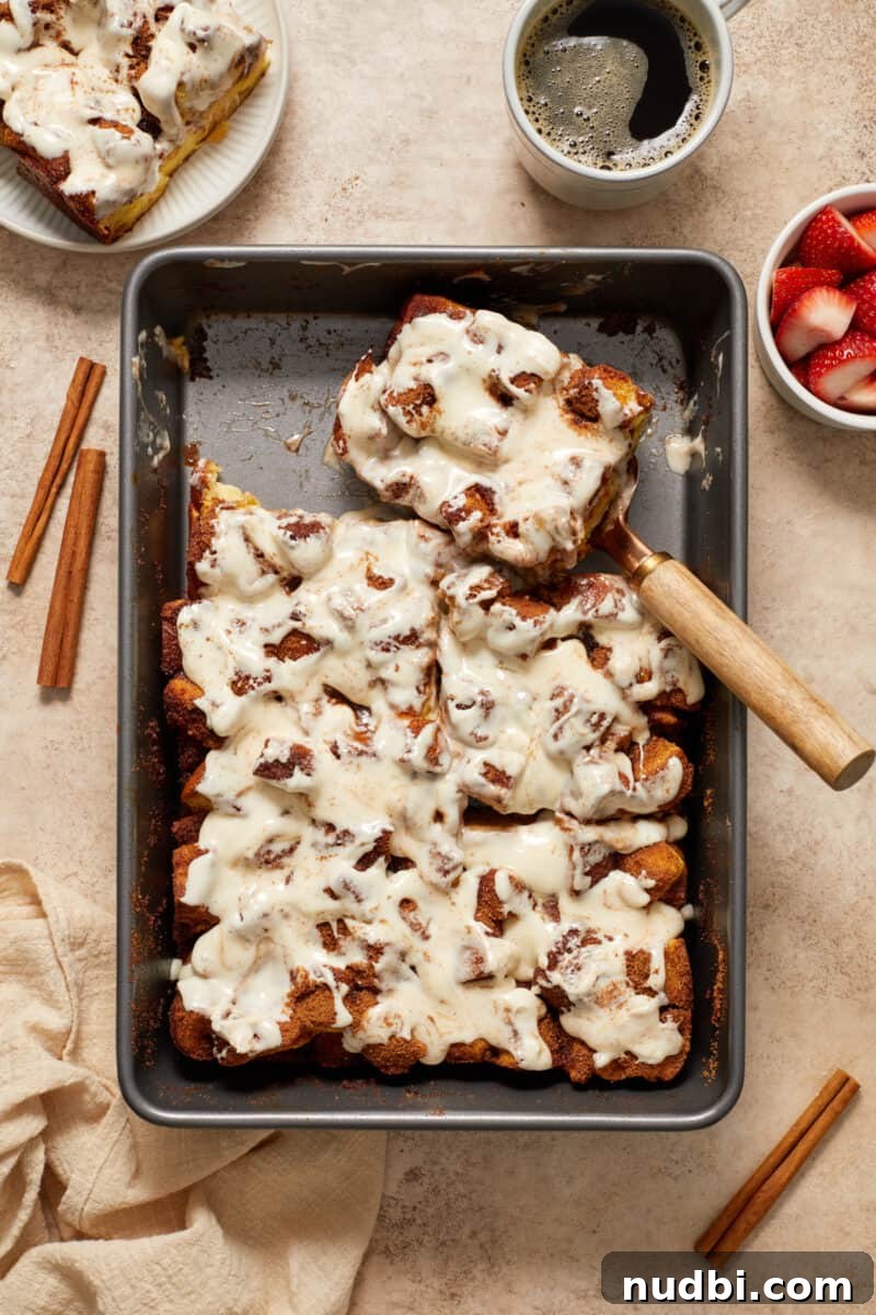 Cinnamon Roll Baked French Toast Recipe for Brunch 12 Slice of baked French toast casserole topped with cream cheese frosting set aside in baking pan.