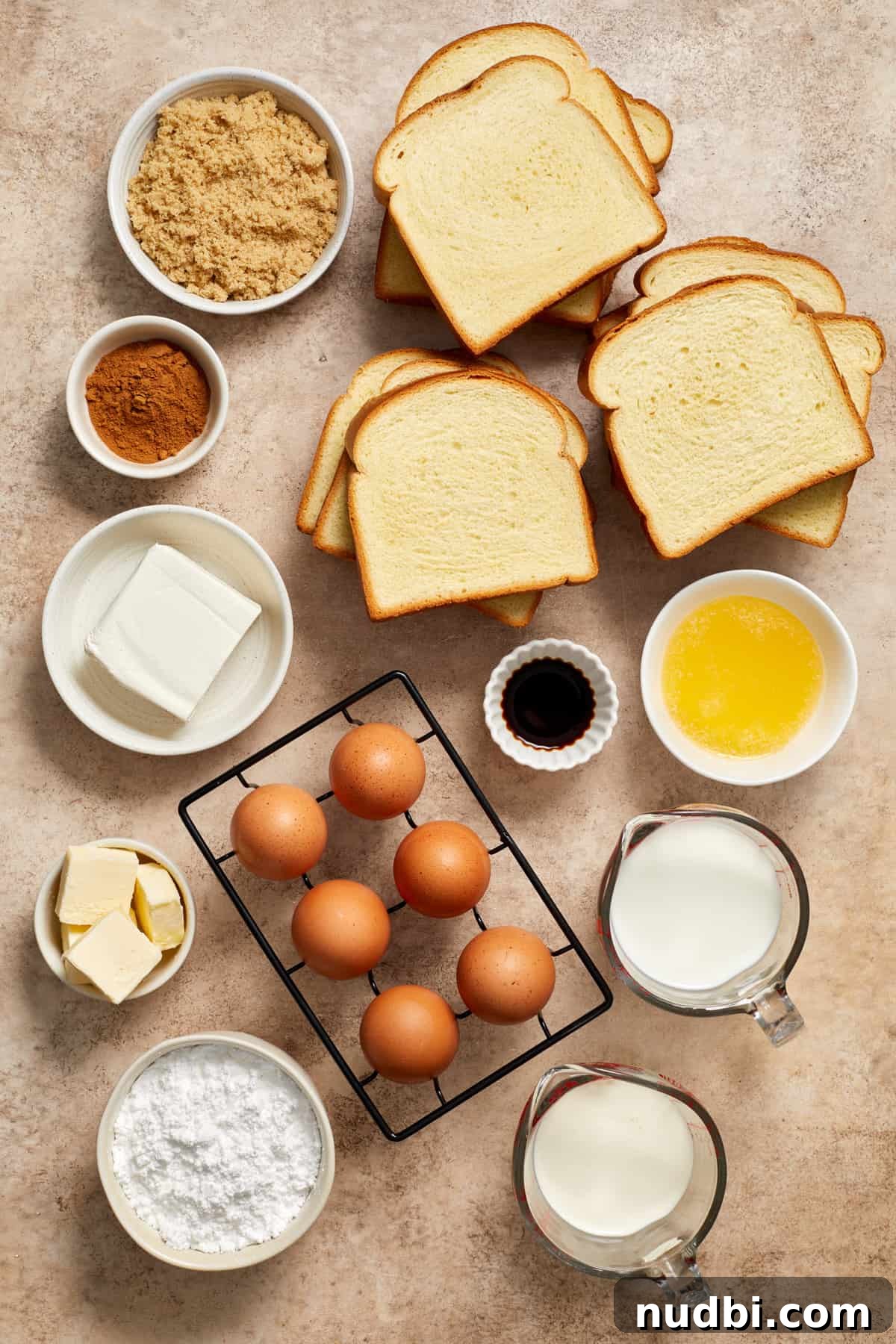 Cinnamon Roll Baked French Toast Recipe for Brunch 4 Eggs, milk, cream, butter, Brioche bread and other ingredients arranged on surface.