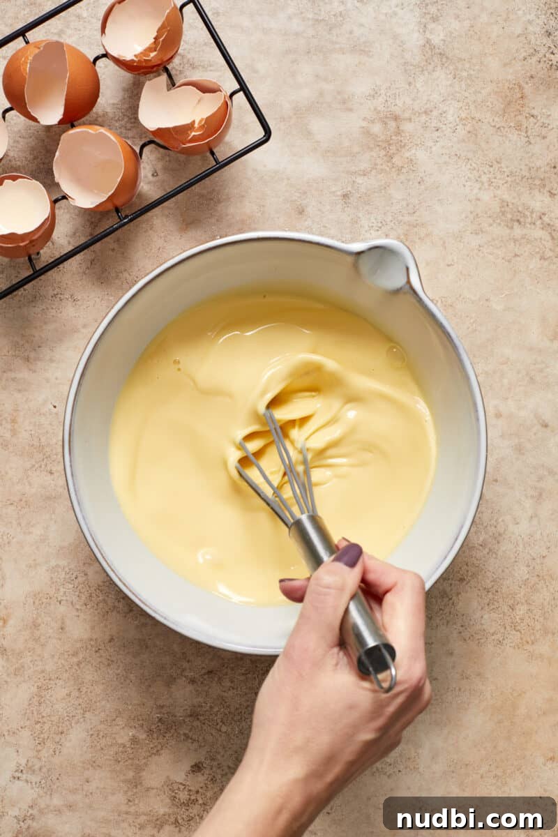 Cinnamon Roll Baked French Toast Recipe for Brunch 5 Whisk stirring egg mixture in mixing bowl.