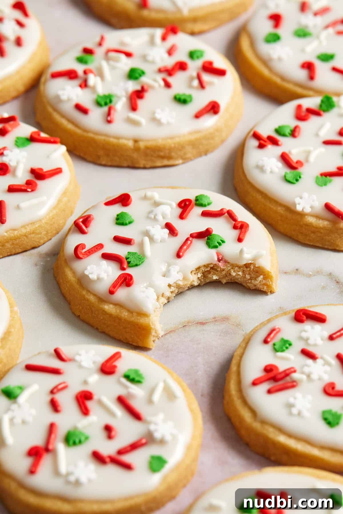 Classic Christmas Shortbread Cookies Recipe for the Holidays 3 Christmas iced cookies arranged on surface with bite taken out of center cookie.