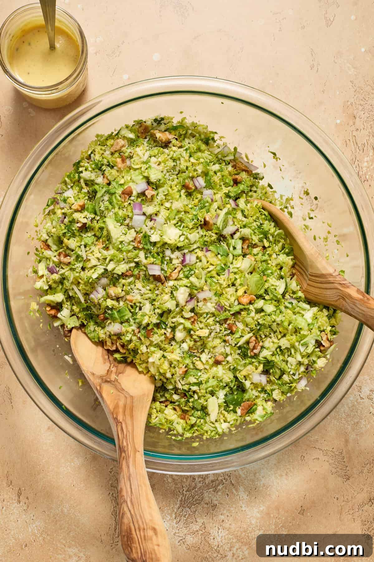 Crisp Shaved Brussels Sprout Salad with Lemon Parmesan Dressing 7 Tossed Brussels sprouts, onion, walnuts and parmesan in salad bowl.
