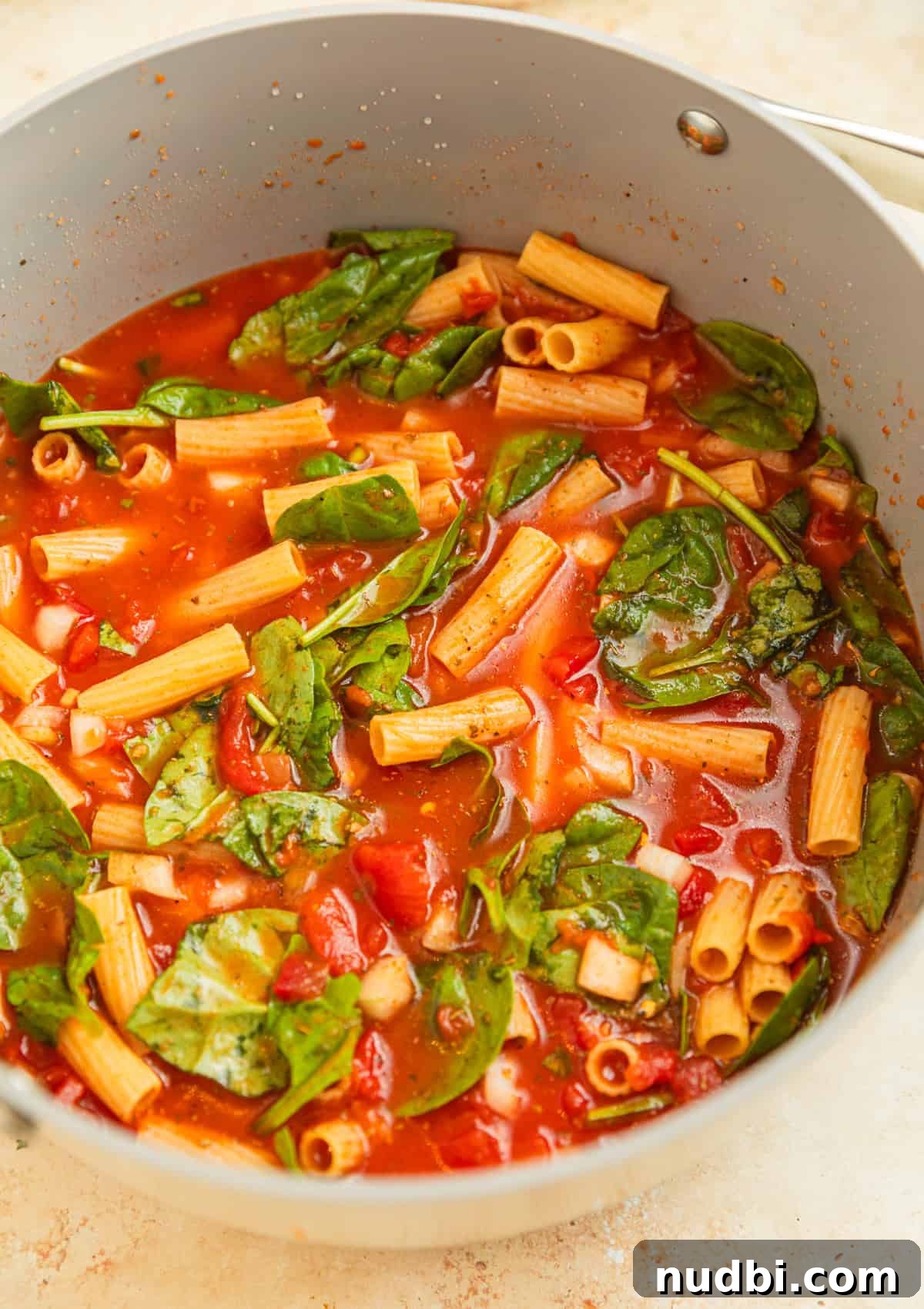 Creamy One-Pot Pasta Recipe for Quick Weeknight Meals 4 Pot with pasta, broth, spinach, and tomatoes.
