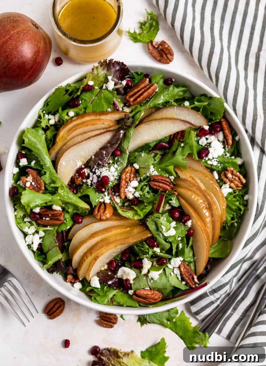 Warm Roasted Pear Salad with Goat Cheese and Candied Pecans 6 Overhead view of pear salad in white bowl with dressing and table linen.