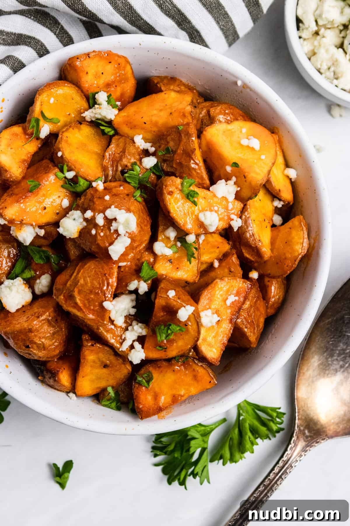 Crispy Buffalo-Style Air Fryer Baby Potatoes 6 Diced potatoes in bowl with buffalo sauce.