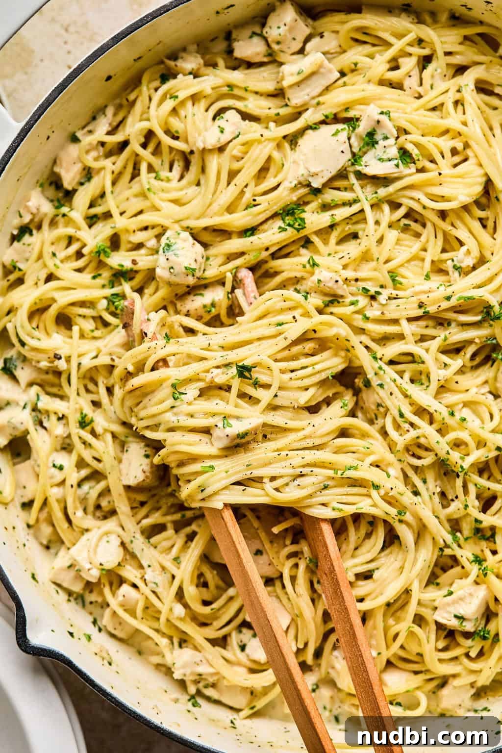 Creamy Chicken Alfredo Dinner Recipe in 30 Minutes 2 One pot easy chicken alfredo in pan with tongs wrapping pasta.