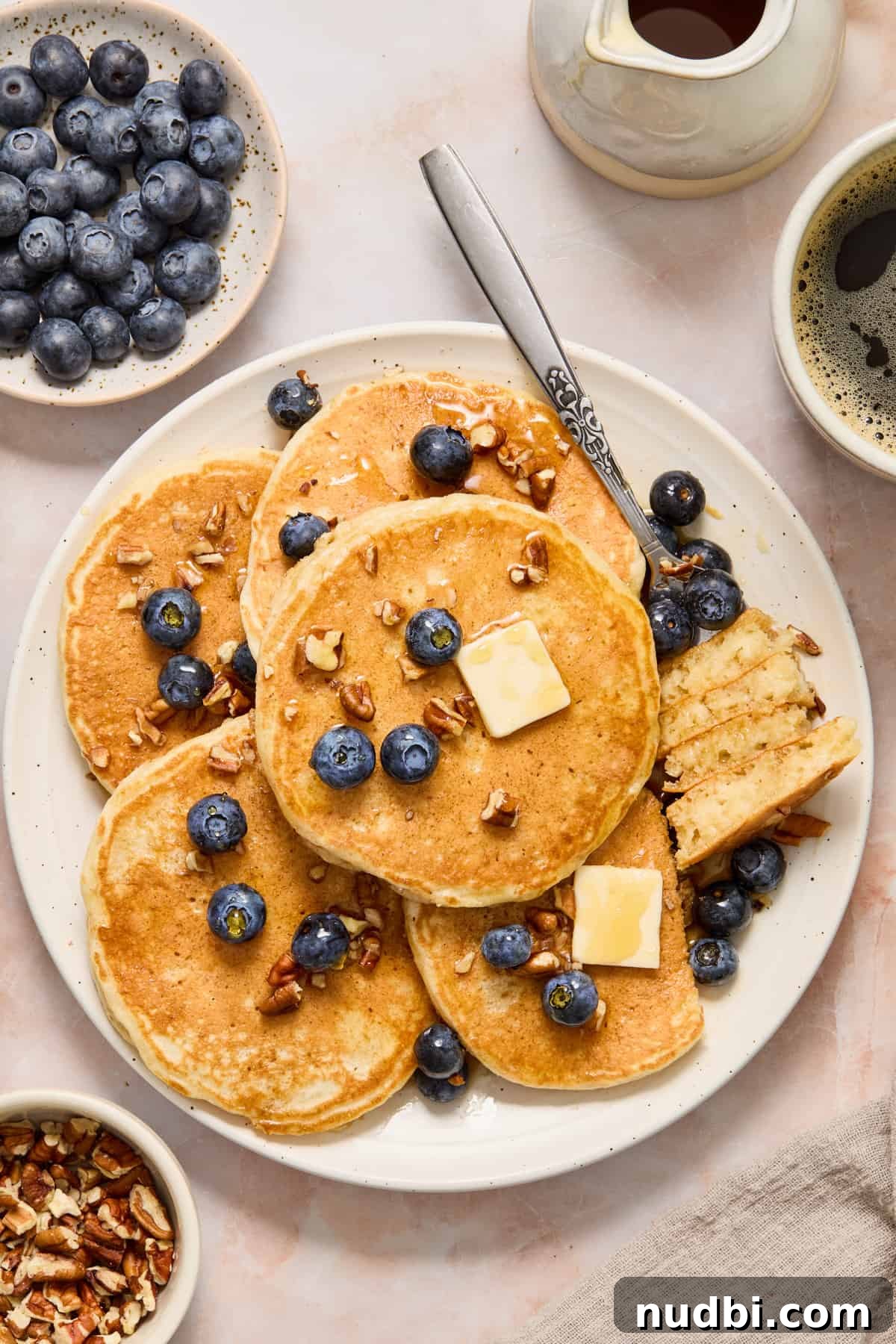 Plate with extra thick and fluffy pancakes with fork holding cut pancake pieces.