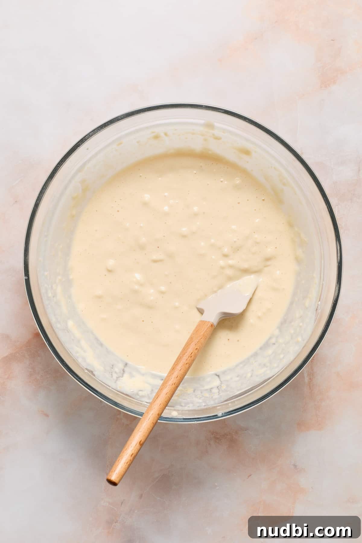 Wet and dry ingredients of pancake batter combined in glass bowl.