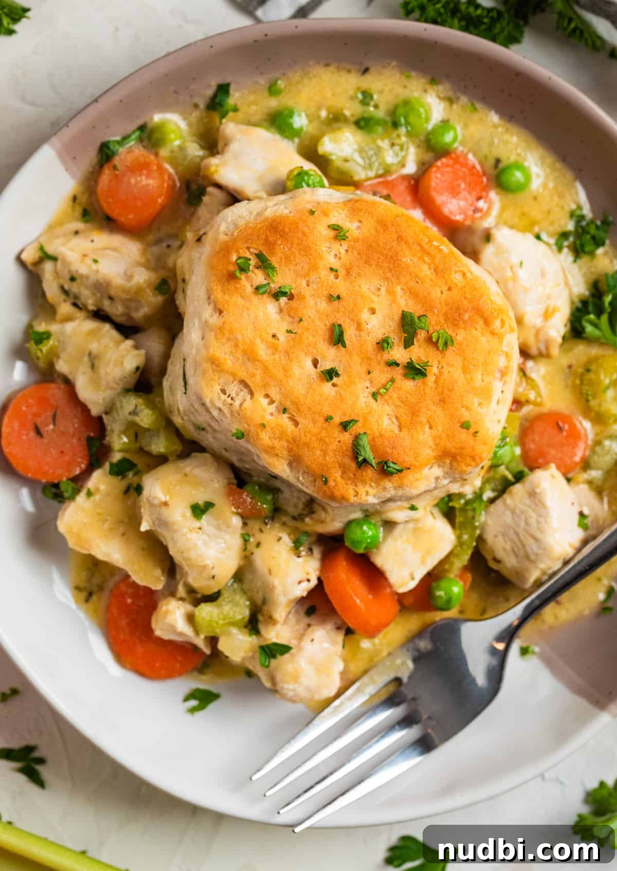One-Pan Chicken and Biscuits Skillet Recipe 11 Overhead view of chicken and biscuit on plate with fork and topped with chopped fresh parsley.