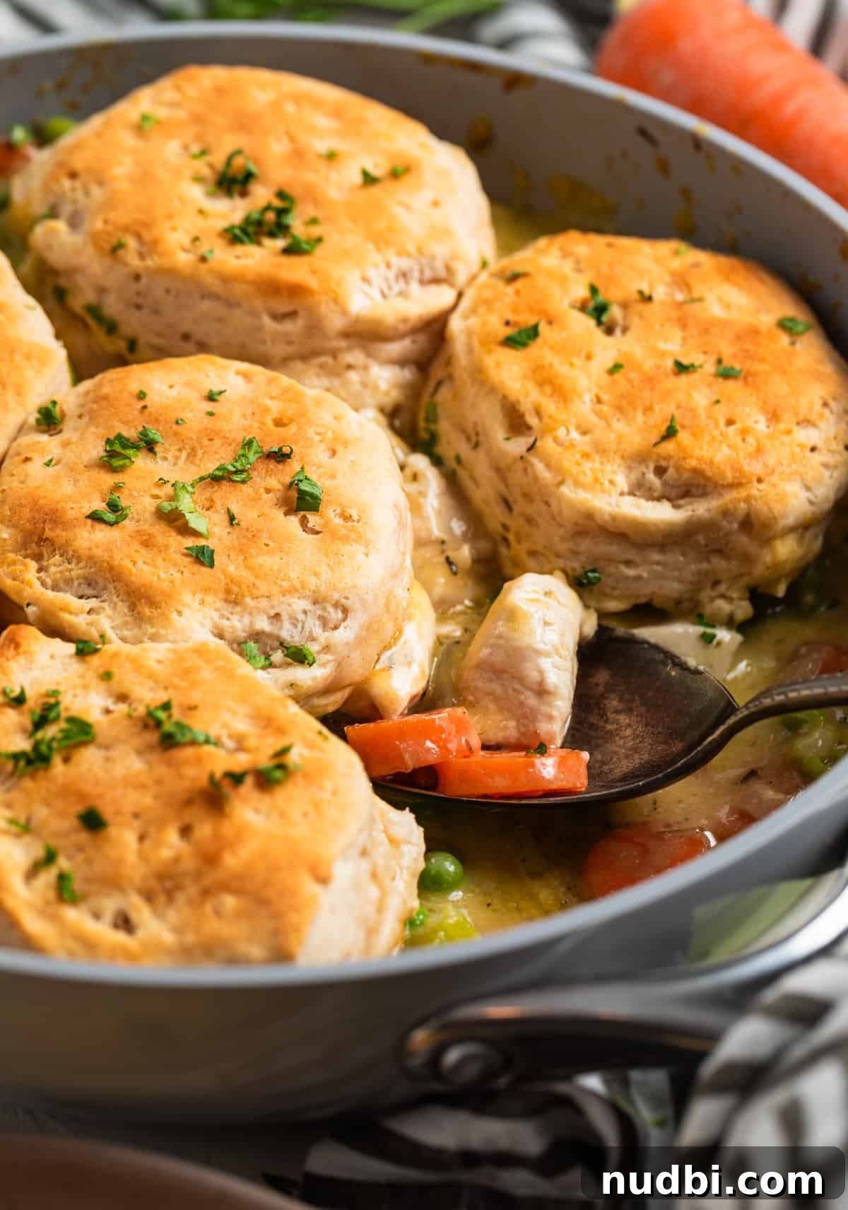 One-Pan Chicken and Biscuits Skillet Recipe 10 Skillet with chicken and biscuits and serving spoon scooping into it.
