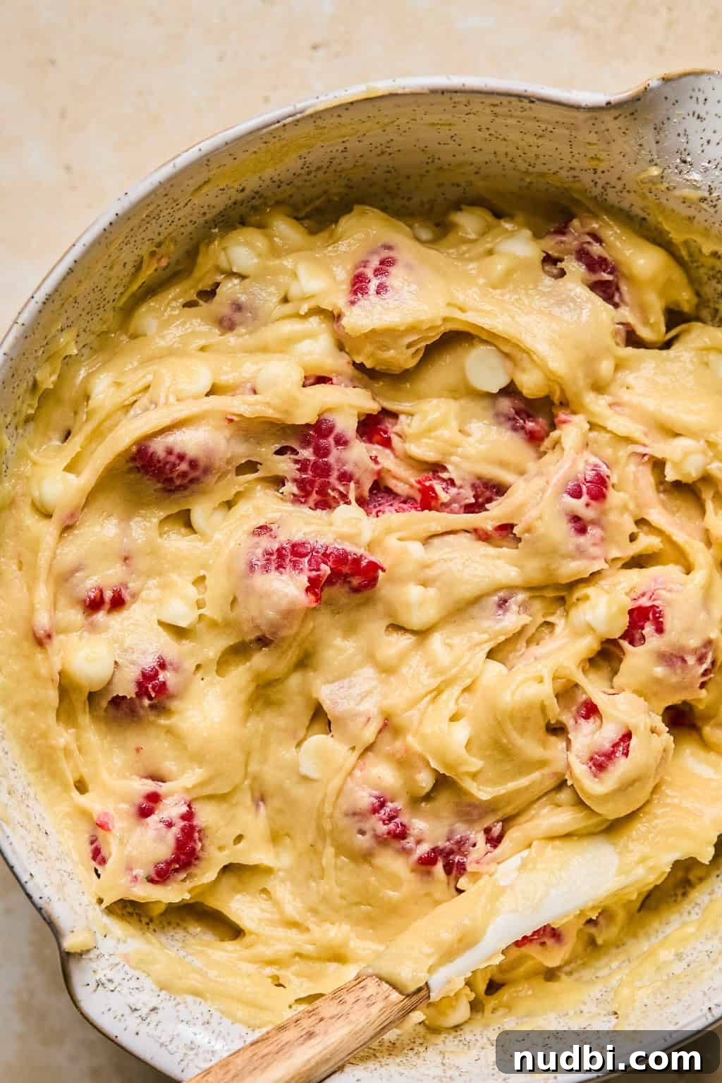 White Chocolate Raspberry Muffins Recipe — Moist, Fruity Treat 11 Raspberry chip muffins batter in bowl with spatula.