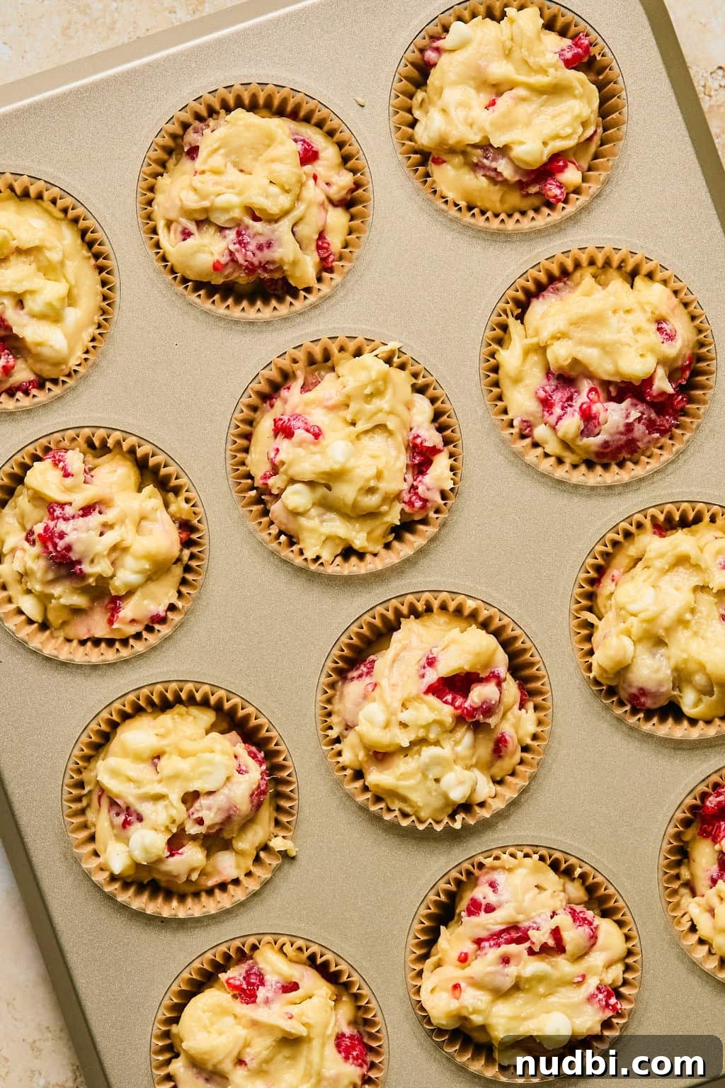 White Chocolate Raspberry Muffins Recipe — Moist, Fruity Treat 9 Muffin batter evenly scooped into muffin lined muffin pan.