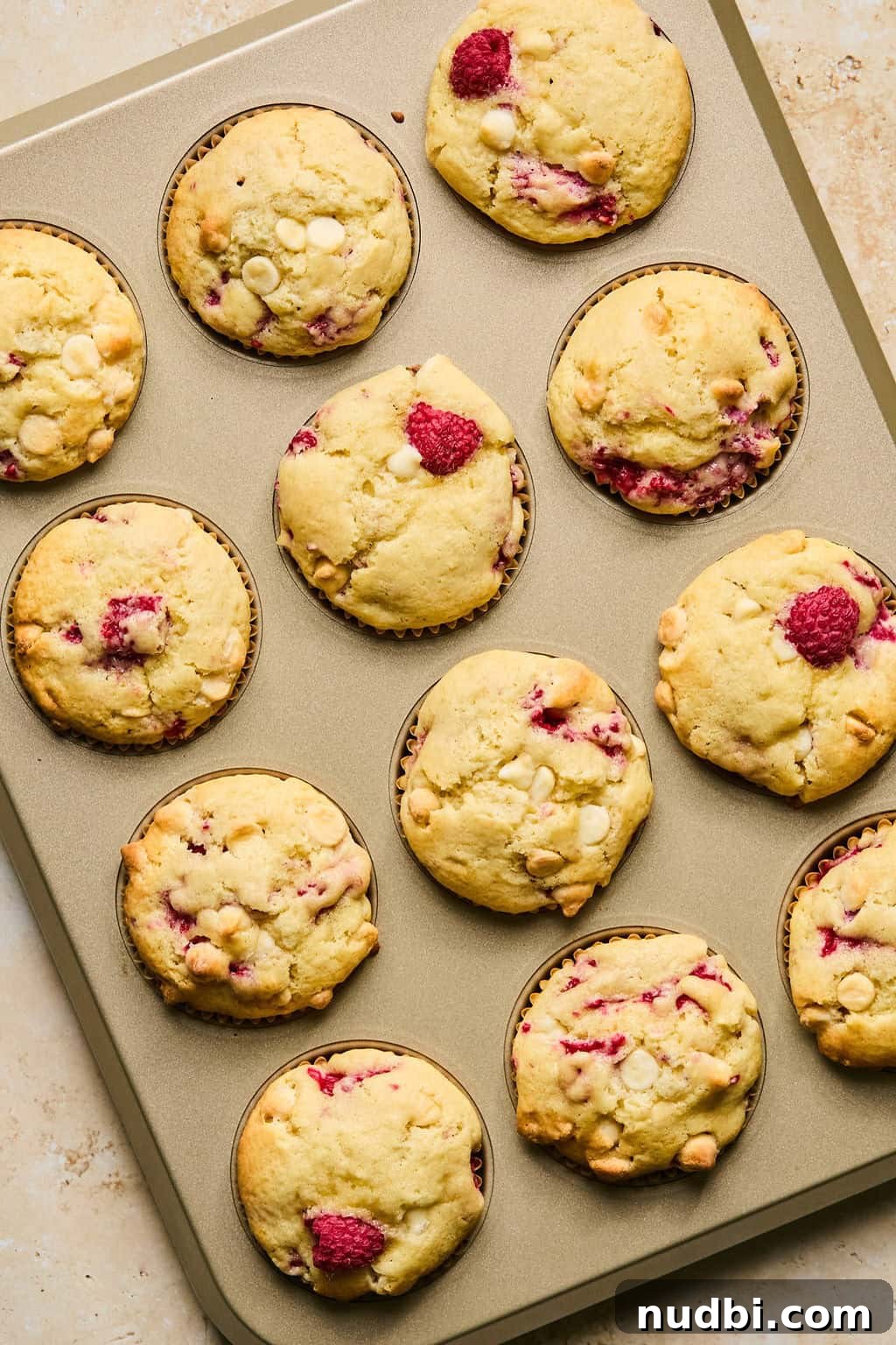 White Chocolate Raspberry Muffins Recipe — Moist, Fruity Treat 10 Baked white chocolate chip and raspberry muffins in muffin tin.