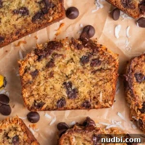 Slice of coconut banana bread with melty chocolate chips on parchment paper.