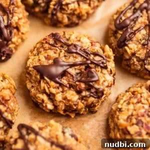 Oatmeal cookies with peanut butter and banana on parchment paper with chocolate drizzle over top.