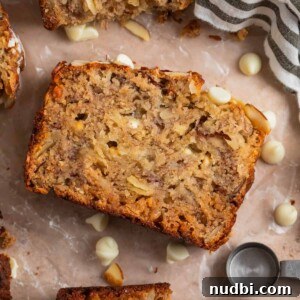 Banana bread slice with white chocolate chips and other slices surrounding.