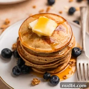 Stack of hot cakes made with bananas and oats topped with butter and maple syrup.