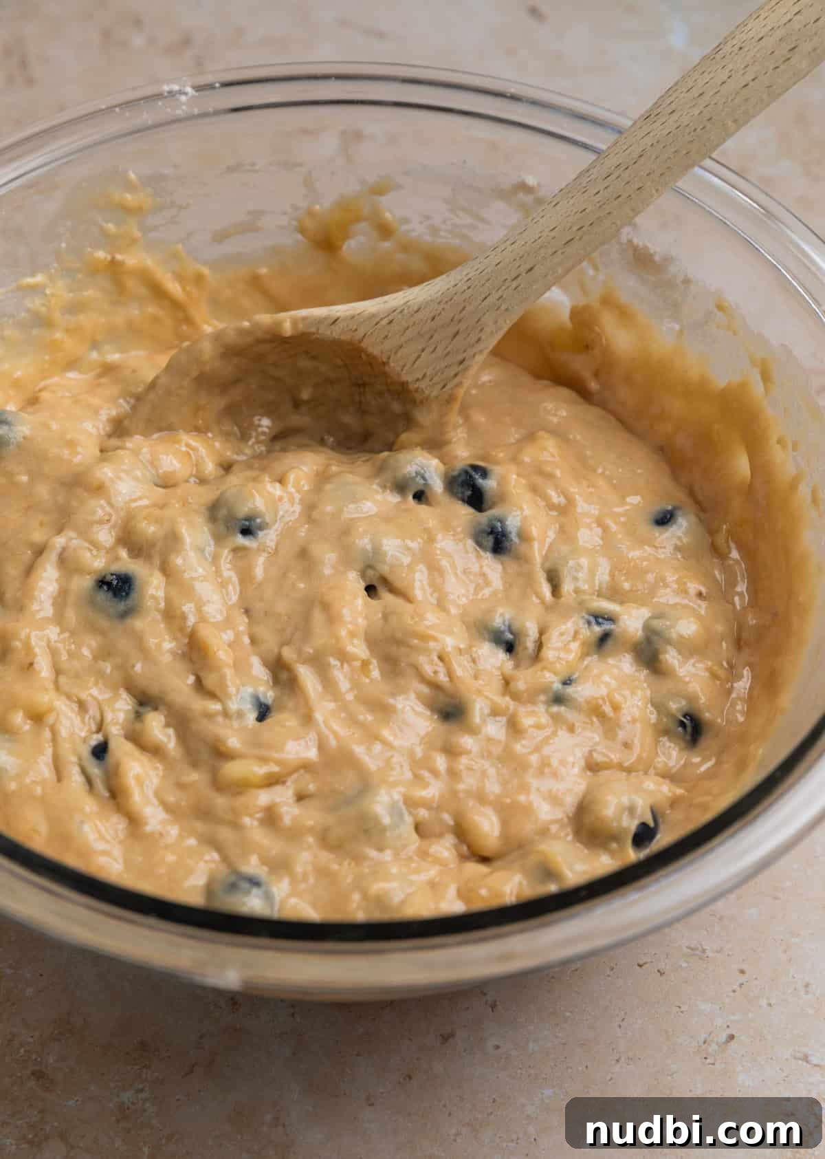 Moist Banana Blueberry Muffins with a Crunchy Streusel 9 Prepared blueberry banana muffin batter in bowl with wood spoon.