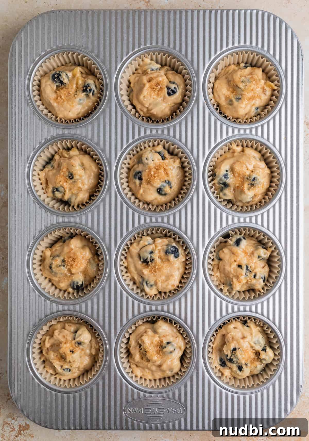 Moist Banana Blueberry Muffins with a Crunchy Streusel 10 Blueberry banana muffin batter scooped into muffin tin before baking.