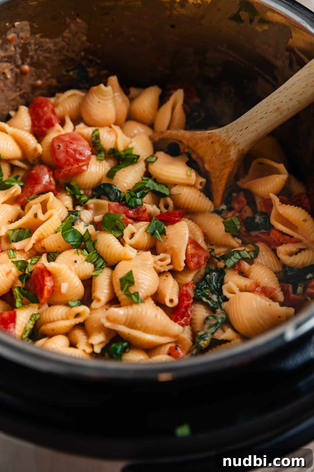 Creamy Parmesan Pasta Made in the Instant Pot in 20 Minutes 3 Instant Pot with pasta cooked with tomatoes and spinach and wooden spoon inside.