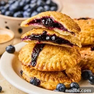 Air Fryer Blueberry Hand Pies Recipe 18 Stack of blueberry hand pies with top broken in half.