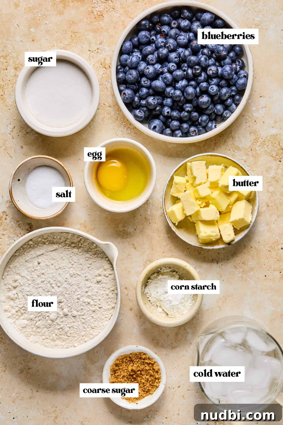 Air Fryer Blueberry Hand Pies Recipe 3 Blueberries, butter, flour and other ingredients labeled on surface.