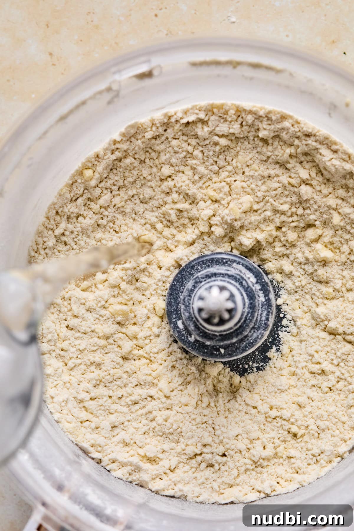Air Fryer Blueberry Hand Pies Recipe 6 Water being poured into food processor with butter and flour mixture.